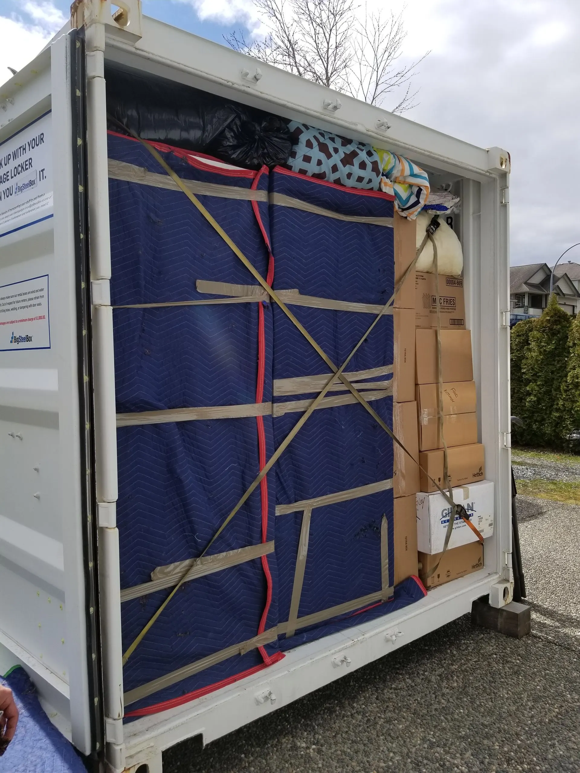 Furniture wrapped in moving blankets and strapped inside a container for transport