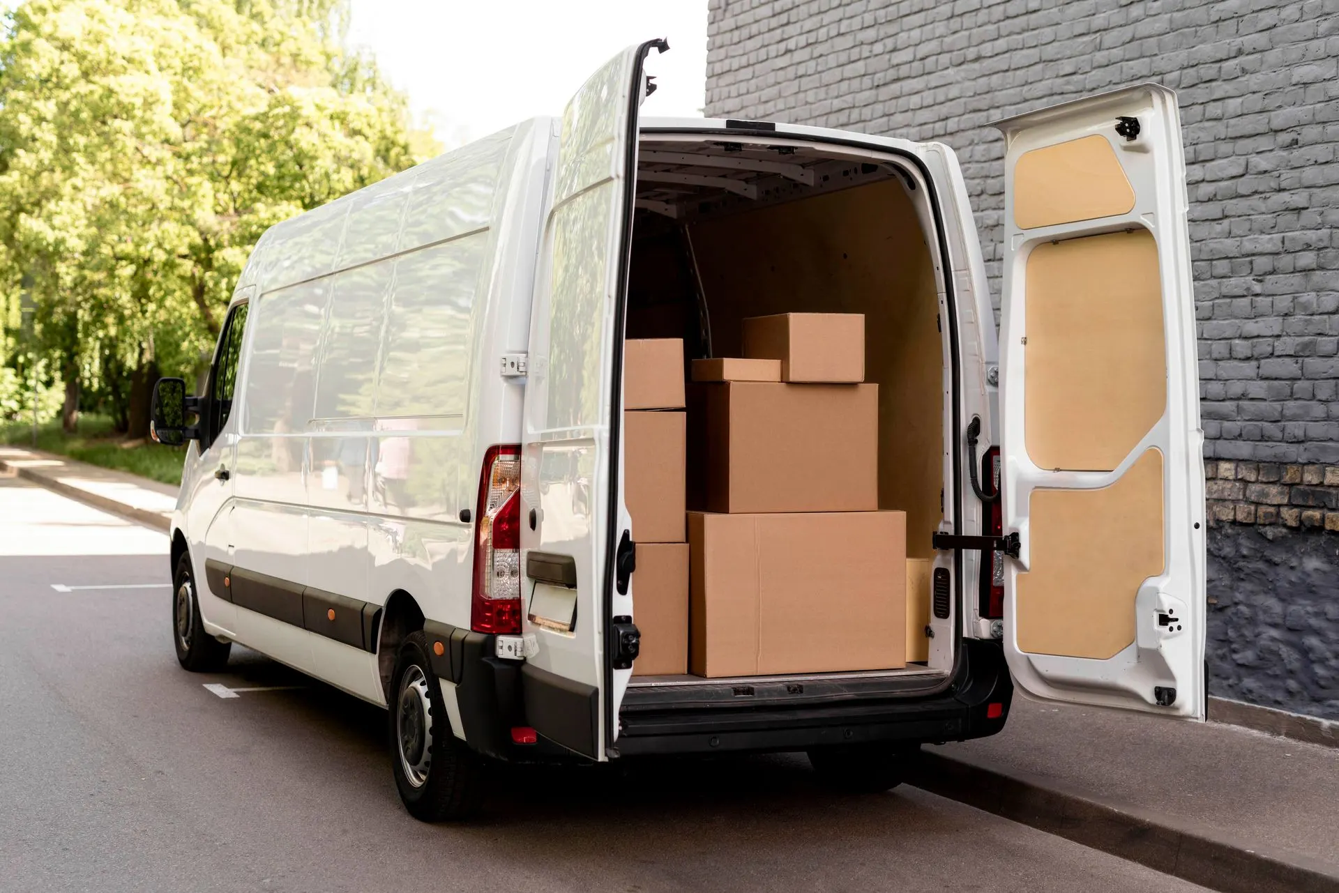White moving van with rear doors open, loaded with cardboard boxes